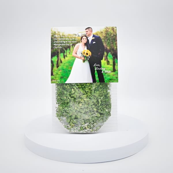 Wedding favor with a photo of a couple and a thank you message, filled with green confetti.
