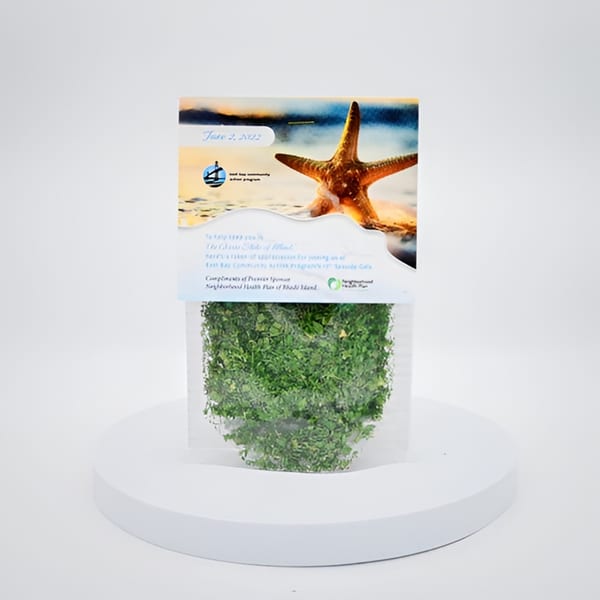 A clear plastic bag filled with green leafy herbs, topped with a beach-themed label featuring a starfish.